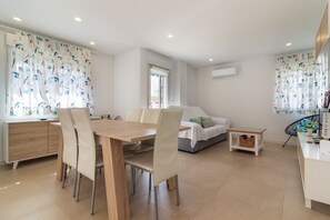 Un salon moderne comprenant un coin repas, un canapé, une petite table et une fenêtre avec des rideaux.