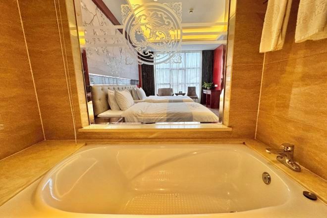 Une grande baignoire donnant sur une chambre, qui comprend un lit et un coin salon.