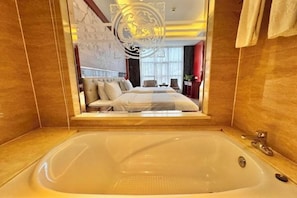 Una bañera grande con vistas a un dormitorio, que incluye una cama y una zona de estar.