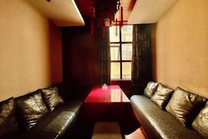 A room with a red table, two leather sofas, and a window with curtains. - Yongshun Minzu Hotel (Yongshun)