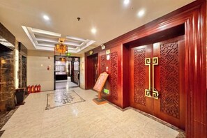 A hotel lobby with a marble floor, wooden doors with intricate carvings, and a modern ceiling design. - Yongshun Minzu Hotel (Yongshun)
