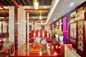A restaurant interior with high tables, red cushioned booths, and traditional decor. - Yongshun Minzu Hotel (Yongshun)
