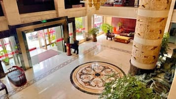 Un vestíbulo amplio con un diseño decorativo en el suelo, una escalera y una columna grande.