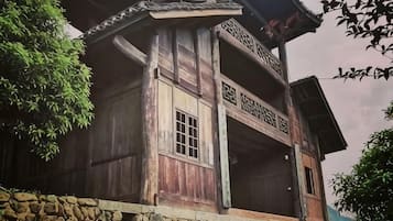 Ein traditionelles Holzhaus mit Balkon, Stein Fundament und einem verzierten Dach.