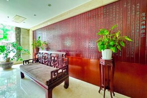 A traditional-style room with a wooden bench, a potted plant, and a wall with calligraphy. - Yongshun Minzu Hotel (Yongshun)