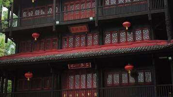 Un edificio tradicional con varios balcones, faroles rojos y ventanas de madera con celosías decorativas.