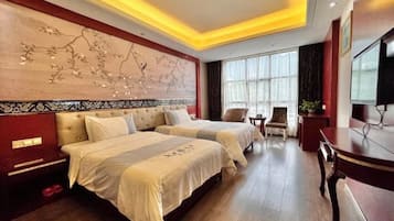 Habitación de hotel con dos camas, televisión, escritorio y un amplio ventanal.