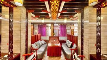 A hotel lobby with a central dining table, seating arrangements, and decorative elements.