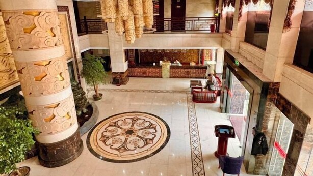 A spacious lobby with a central decorative column, a patterned floor design, and a reception desk. - Yongshun Minzu Hotel (Yongshun)