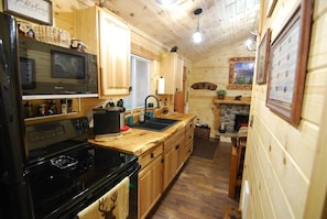 A compact kitchen with wooden cabinets, a microwave, a stove, and a sink.