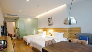 Une chambre d’hôtel avec un plancher en bois, un lit avec une literie blanche, un bureau avec une chaise et une table à manger.