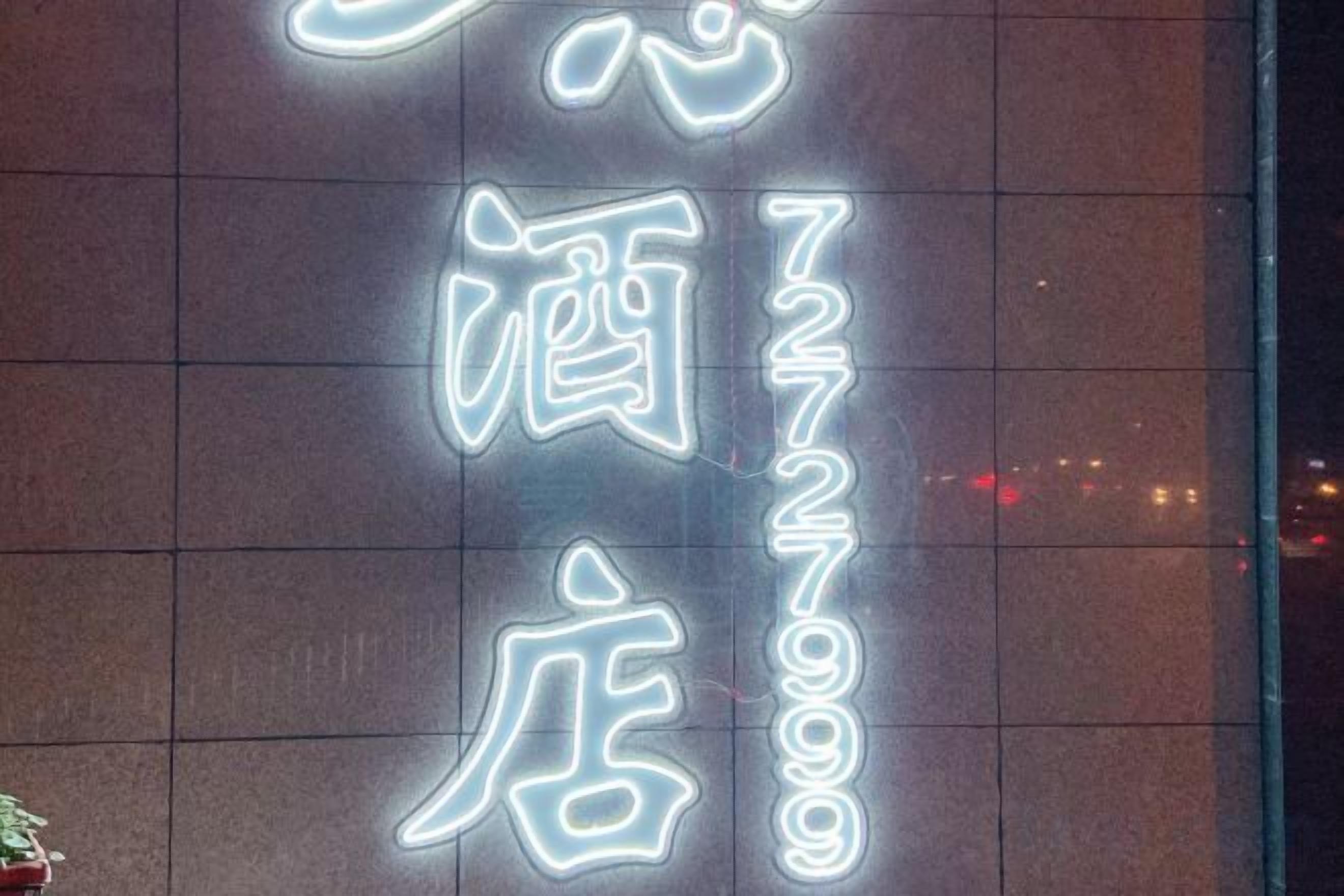 A neon sign with Chinese characters on a building facade.