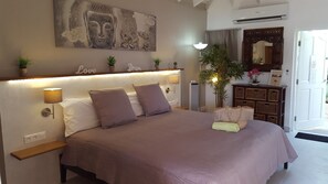 A bedroom with a large bed, bedside lamps, a wall-mounted artwork, and a bedside plant.
