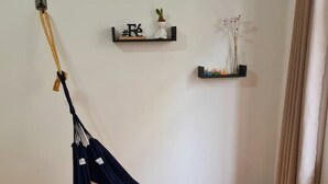 A room with a dark blue hammock, a small shelf with a plant, and a wicker basket on the floor.