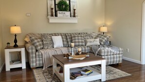 A living room with a plaid sofa, a coffee table, and a fireplace mantel with a wreath and candles. - Pine Ridge Manor • A+ Privacy • Pool • BBQ • Games (Franklin)