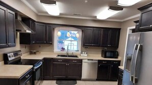A modern kitchen with dark cabinetry, stainless steel appliances, and a large window. - Pine Ridge Manor • A+ Privacy • Pool • BBQ • Games (Franklin)