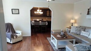 A living room with a sofa, coffee table, and a dining area with a chandelier. - Pine Ridge Manor • A+ Privacy • Pool • BBQ • Games (Franklin)