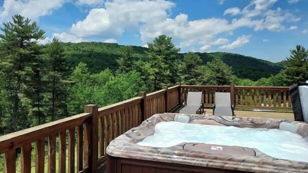 A hot tub on a wooden deck with a view of a forested mountain range. - Pine Ridge Manor • A+ Privacy • Pool • BBQ • Games (Franklin)