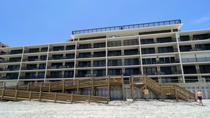 Hotel com vários andares, varandas e uma praia em primeiro plano.