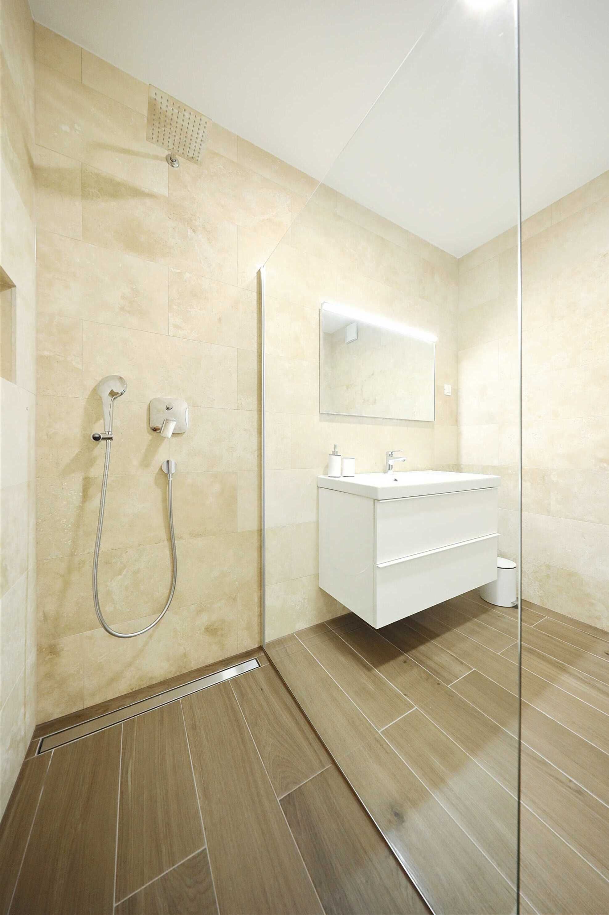 A modern bathroom with a shower, a sink, and a mirror.
