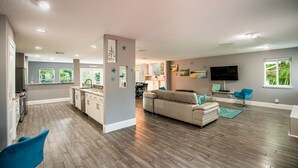 A spacious living area with a kitchen, a beige sofa, and a flat-screen TV.