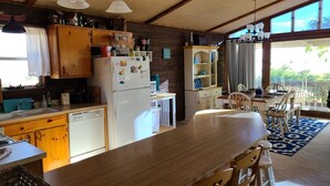 Una cocina con armarios de madera, un refrigerador blanco y un comedor con mesa y sillas de madera.