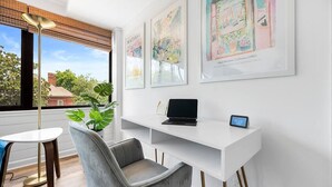 Een moderne kantoorruimte met een wit bureau, een laptop en een klok waarop 1:33 staat.