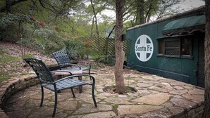 Une terrasse en pierre avec deux chaises en métal, un arbre et un bâtiment sur lequel on peut lire l’inscription « Santa Fe ».