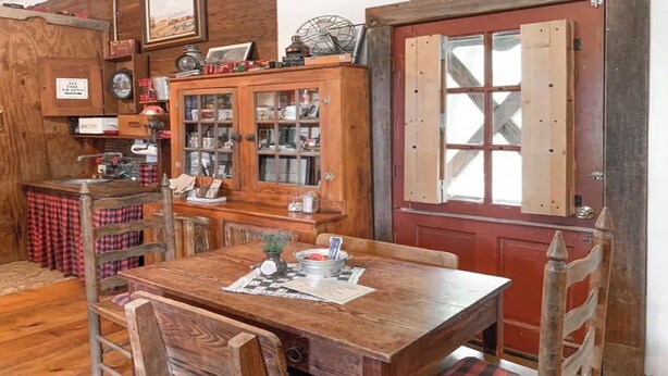 Un coin repas rustique en bois, avec une table, des chaises et un buffet aux portes vitrées.