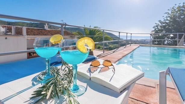 A poolside setting with two blue cocktails, a book, and sunglasses on a table. - Casa Campo Chimenea Rincón de la Victoria by Ruralidays (Málaga)