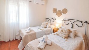 A hotel room with two beds, a nightstand, a lamp, and a wall-mounted air conditioner. - Casa Campo Chimenea Rincón de la Victoria by Ruralidays (Málaga)