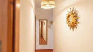 A hallway with a mirror reflecting a door, a woven light fixture, and a sunburst wall decoration. - Casa Campo Chimenea Rincón de la Victoria by Ruralidays (Málaga)
