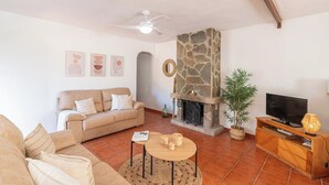 A living room with a stone fireplace, a sofa, a television, and a coffee table. - Casa Campo Chimenea Rincón de la Victoria by Ruralidays (Málaga)