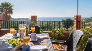 A table set for breakfast with drinks and fruits, overlooking a coastal view. - Casa Campo Chimenea Rincón de la Victoria by Ruralidays (Málaga)
