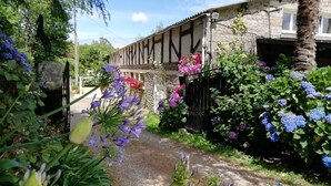 A garden pathway leading to a stone building with a timber-framed structure. - Lodge Domaine de kerolivier a bubble of tranquility with every comfort  (Plogonnec)
