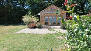 A wooden cabin with a sloped roof, a small porch, and a gravel pathway leading to the entrance. - Lodge Domaine de kerolivier a bubble of tranquility with every comfort  (Plogonnec)