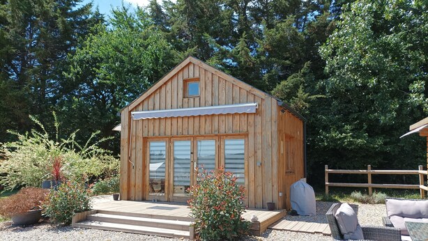 A wooden cabin with a porch, surrounded by gravel and potted plants. - Lodge Domaine de kerolivier a bubble of tranquility with every comfort  (Plogonnec)