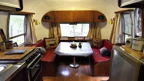 A compact RV interior with a kitchenette, dining area, and seating.