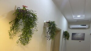 Um corredor com chão de azulejos, porta de madeira e um ar-condicionado fixado na parede.
