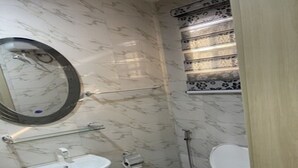 Casa de banho com uma sanita, uma pia branca e um espelho.