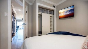 Ein Schlafzimmer mit Bett, Kleiderschrank und Fernseher an der Wand.