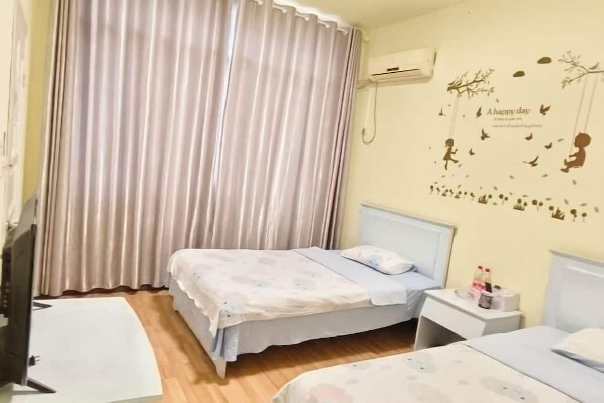 Un dormitorio con dos camas, televisión, mesita de noche y un adorno en la pared.