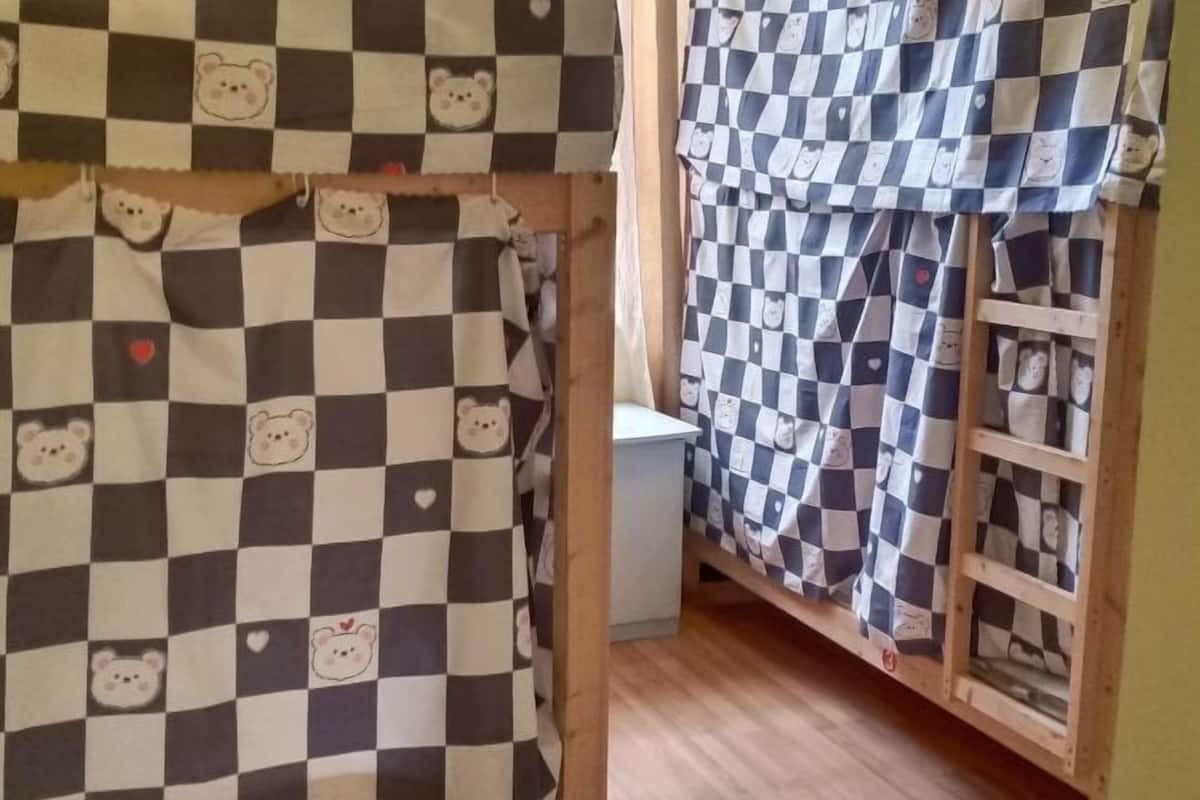 Una habitación con colcha de cuadros con diseños de osos y una escalera de madera.