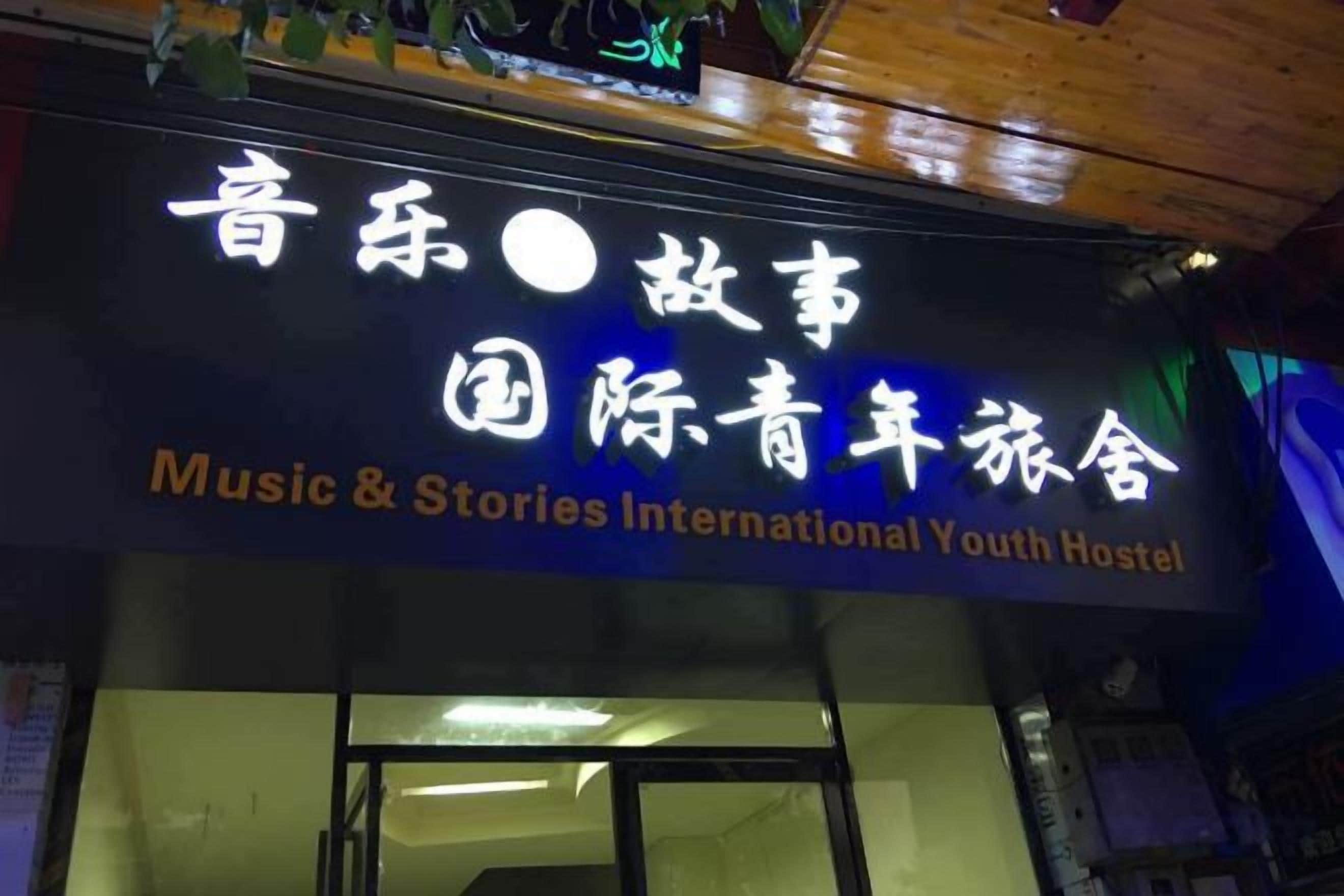 A sign for a hostel with the name 'Music & Stories International Youth Hostel' in both English and Chinese.