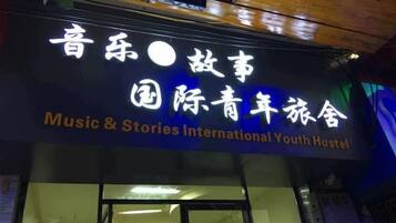 A sign for a hostel with the name 'Music & Stories International Youth Hostel' in both English and Chinese.