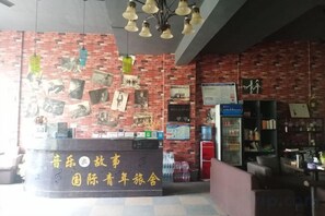 Zona de recepción con pared de ladrillo, mostrador con un letrero y una lámpara colgante.