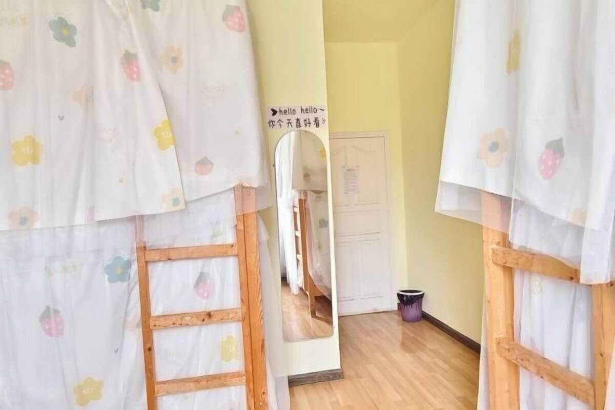 Una habitación con literas, una escalera de madera, un espejo y una puerta con un letrero.