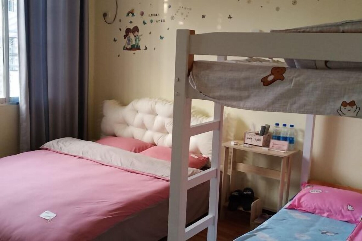 Quarto com beliche, escrivaninha e prateleira pequena, janela com cortinas e detalhes decorativos nas paredes.