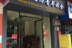 La entrada a un hostal con puerta de vidrio, un cartel con texto y un tablón de anuncios con información.