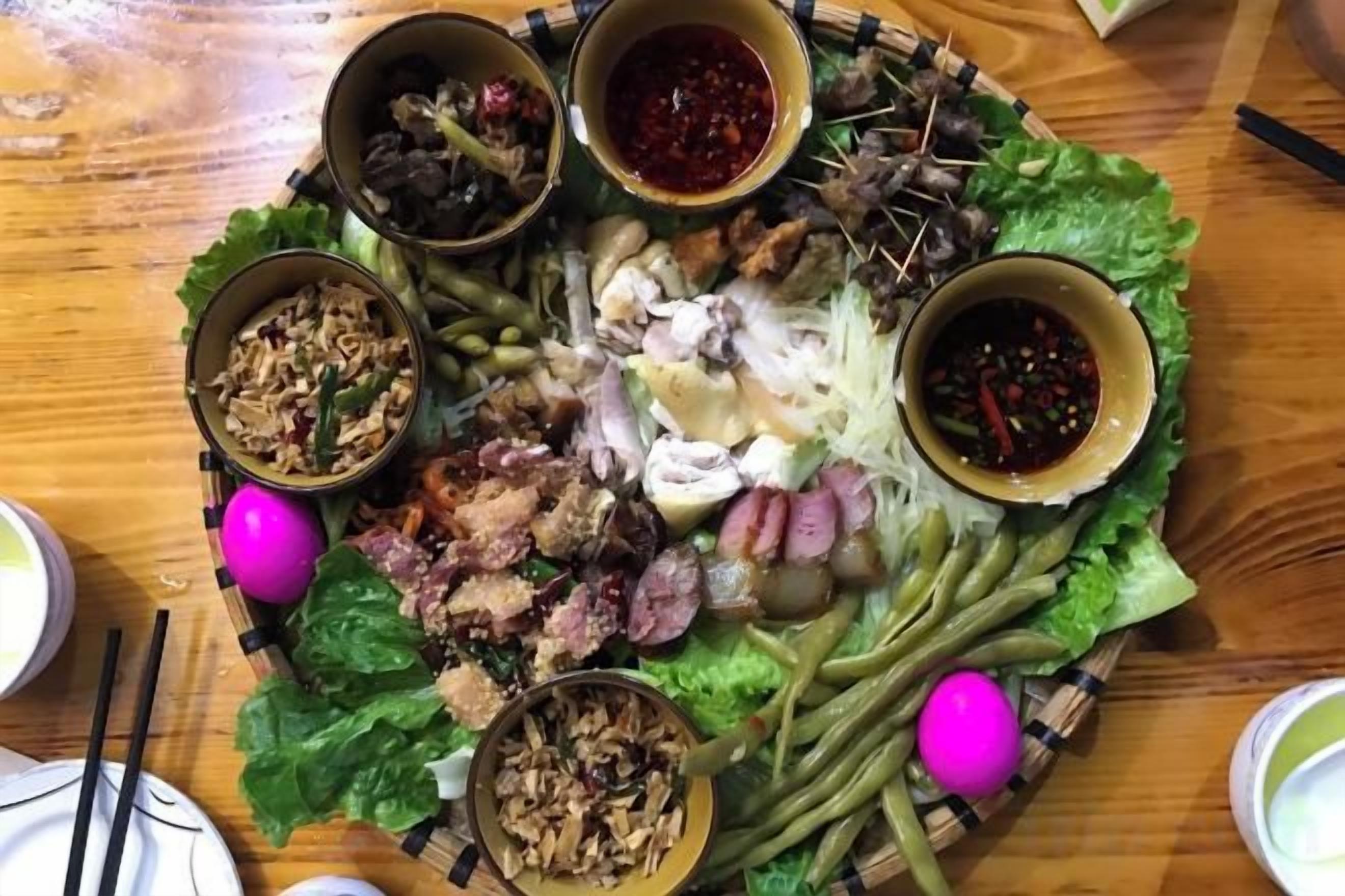 A table with various food items and condiments, including meat, vegetables, and sauces.